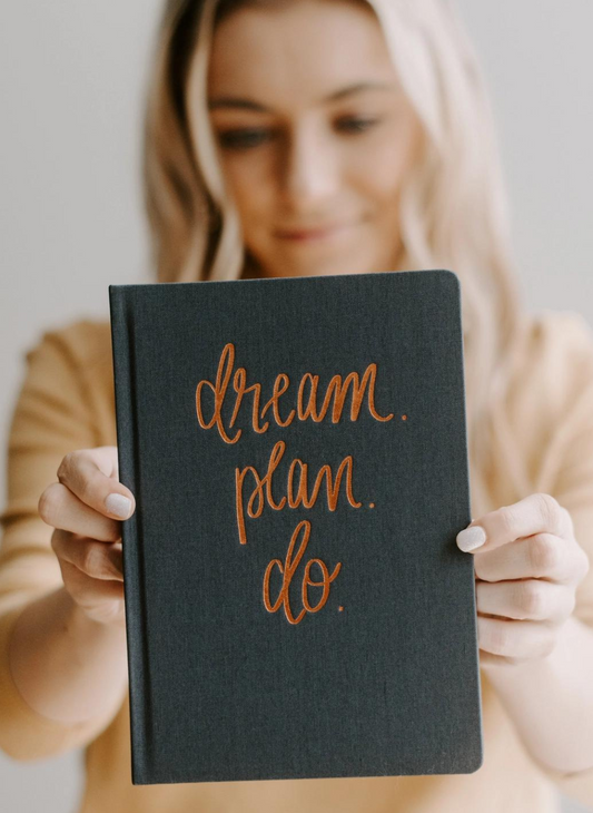 Model holding hand lettered Dream Plan Do, Grey and Rose Gold Fabric Journal.