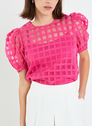 Front view of model wearing pink Off the Grid Top tucked into white pants with hand in pocket.