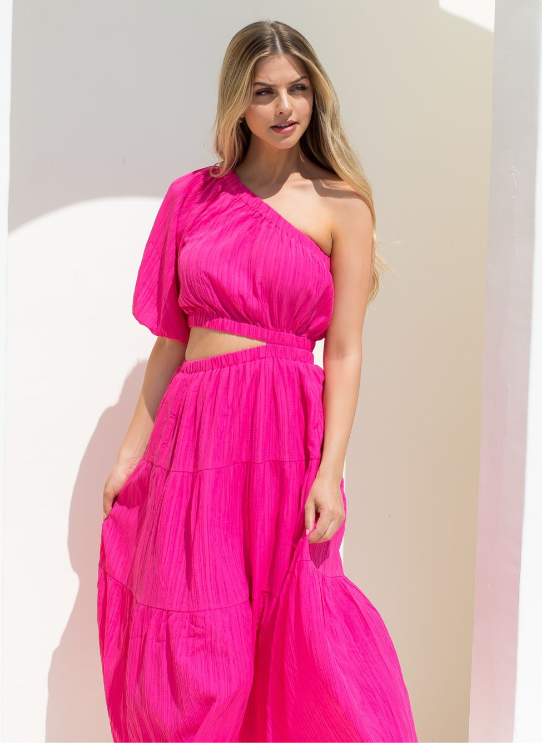 Model wearing fuchsia vibrant Grecian Dream Maxi Dress with one shoulder design and waist cutout detail.