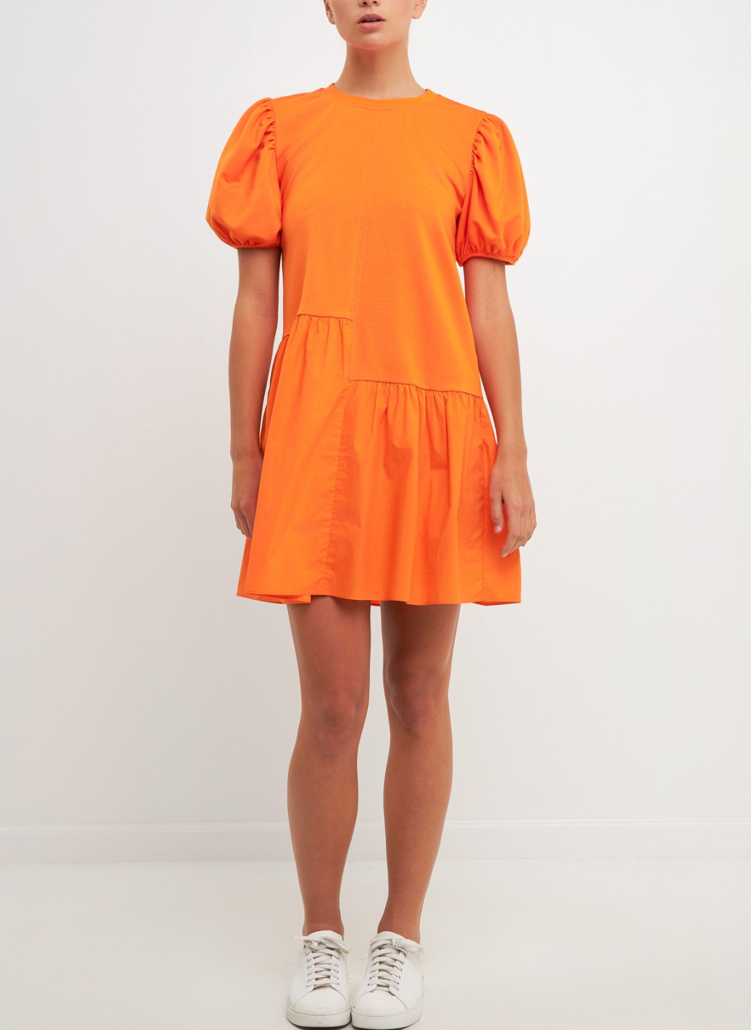 Full body view of model wearing Orangesicle Delight Dress with short puffy sleeves, knit bodice, cotton poplin skirt, and uneven front seam at the waist. White background.