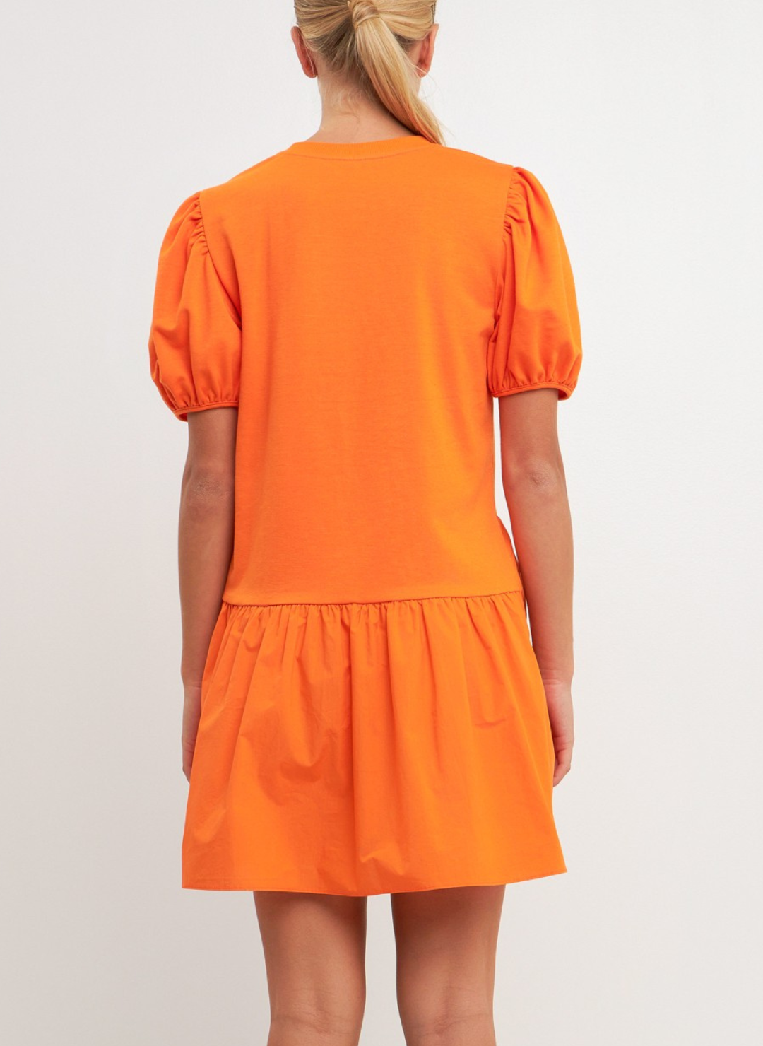 Back view of model wearing Orangesicle Delight Dress with short puffy sleeves, knit bodice, and cotton poplin. White background.
