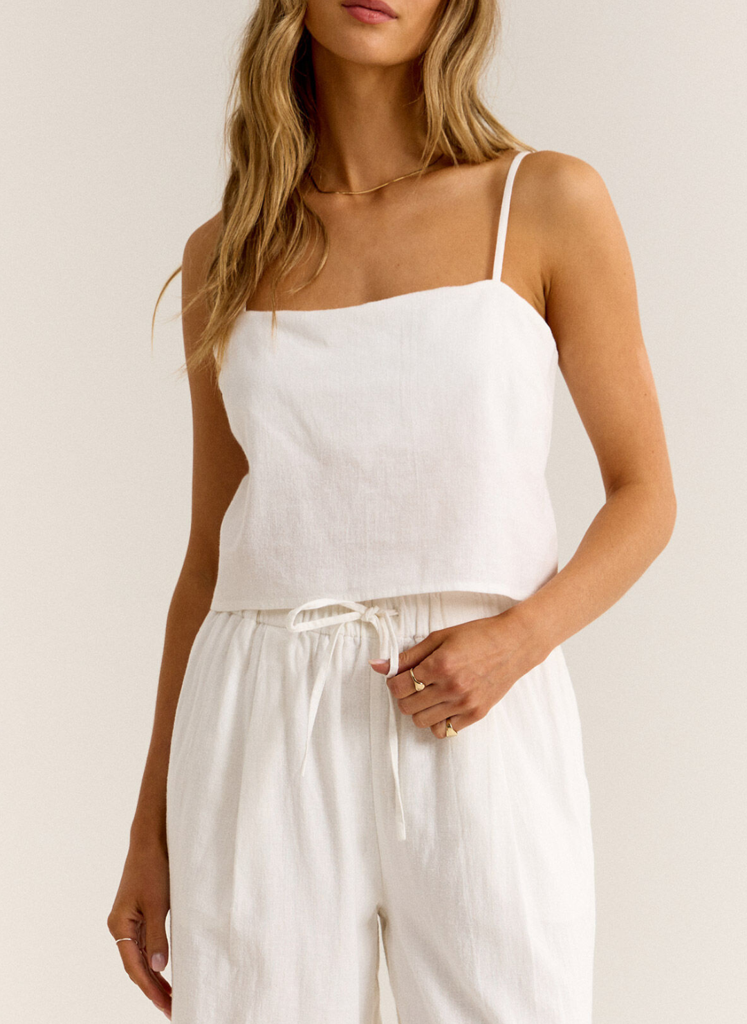 Closer view of model wearing White Ballast Tank paired with white linen pants. Front view.