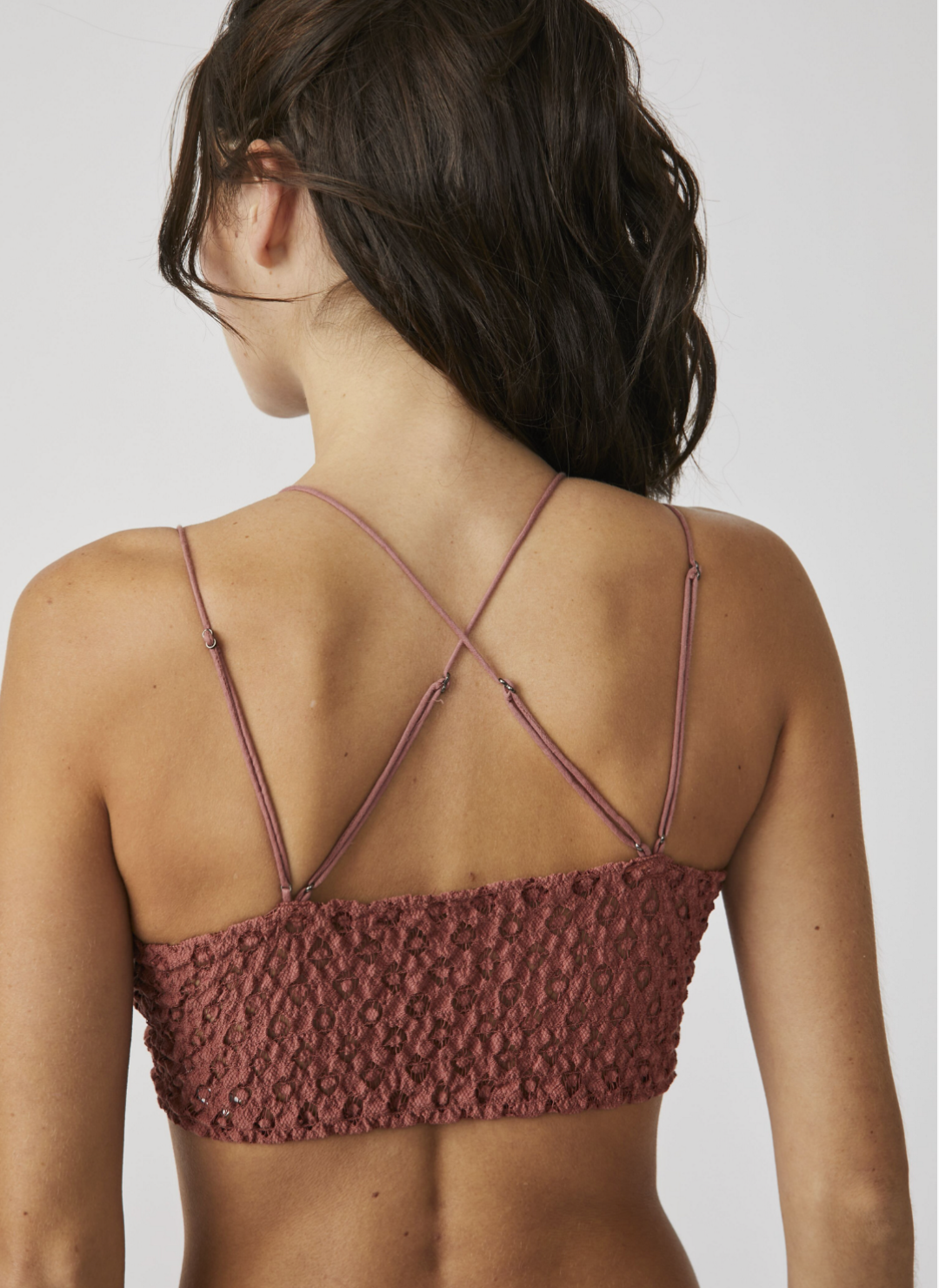 Model facing away wearing Red Adella Bralette showing the criss cross design of the straps and textured lace back design.