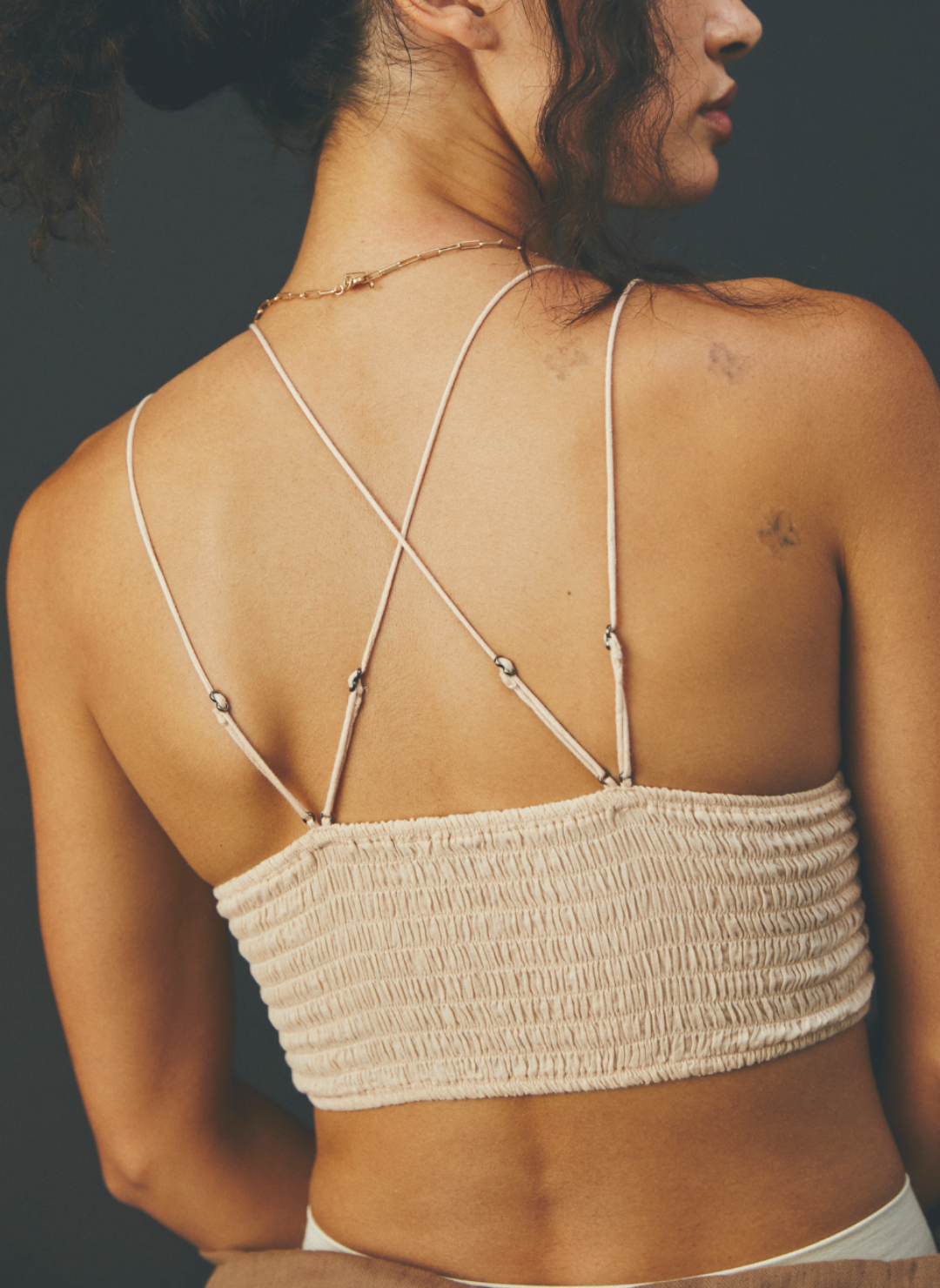 Model facing away wearing color Camel Adella Bralette showing the criss cross design of the straps on the back of the bralette. 