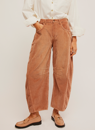Pictured a corduroy pant in a rust color.  Darts at the inner knee and a tapered hem.  White shirt paired with it and loafers.