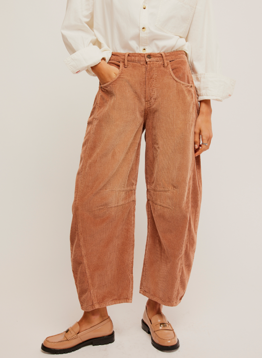 Pictured a corduroy pant in a rust color.  Darts at the inner knee and a tapered hem.  White shirt paired with it and loafers.