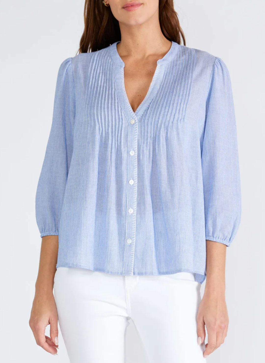 Model wearing LS Cloudy Skies Top with a split v-neckline, 3/4 length sleeve, and elastic cuff. Features a button front with a crochet stitch border and pintuck details styled with white jeans.