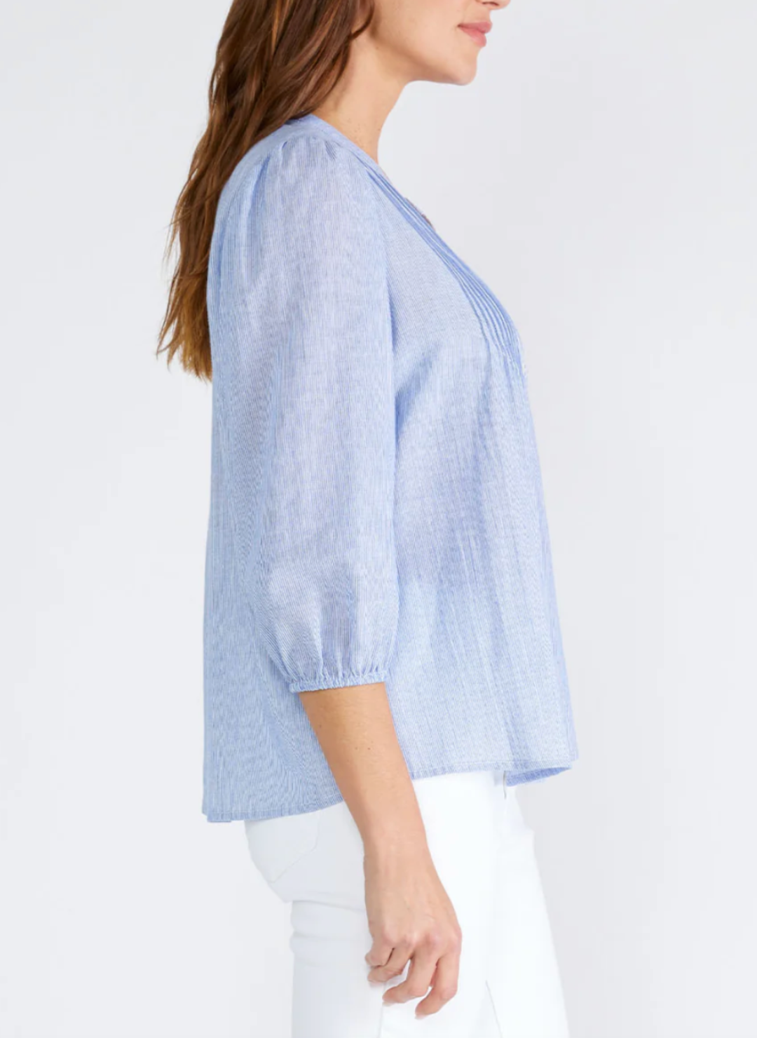 Side view of model wearing LS Cloudy Skies Top with a split v-neckline, 3/4 length sleeve, and elastic cuff. Features a button front with a crochet stitch border and pintuck details styled with white jeans.