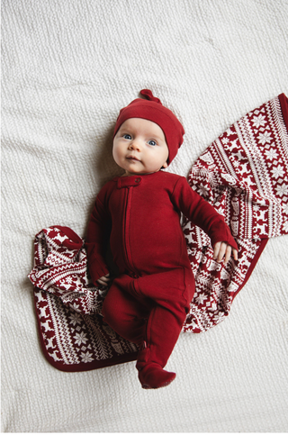 Baby lying on red and white Fair Isle thermal blanket in organic cotton by L’ovedbaby