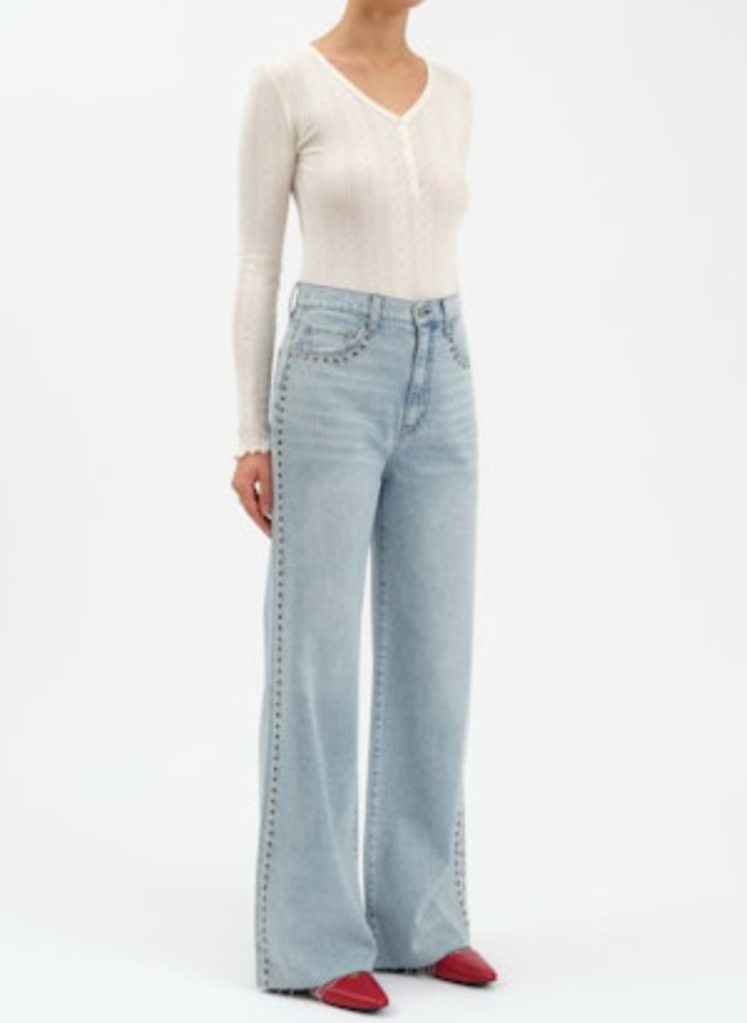 Person wearing light blue jeans and a white long-sleeve top on a white background