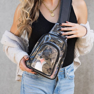 Woman wearing the clear Stadium Sling Bag with black trim as a crossbody over a black top and light denim jeans.