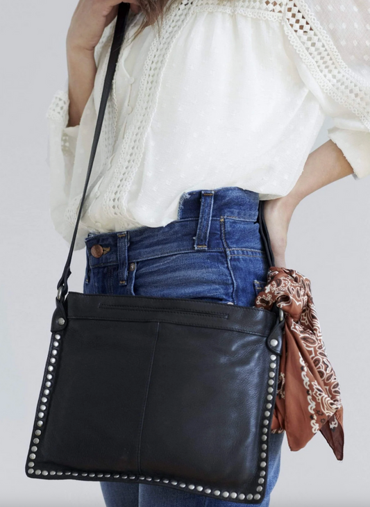 Woman wearing black Latico Gabriel Crossbody with studded trim, styled with jeans and blouse