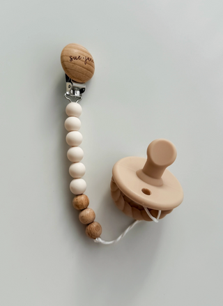 Wooden pacifier clip with beads and a wooden pacifier on a light gray background