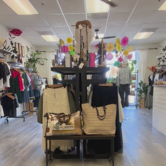 A woman walking with the denim shirt on, black denim jeans inside of August Boutique.
