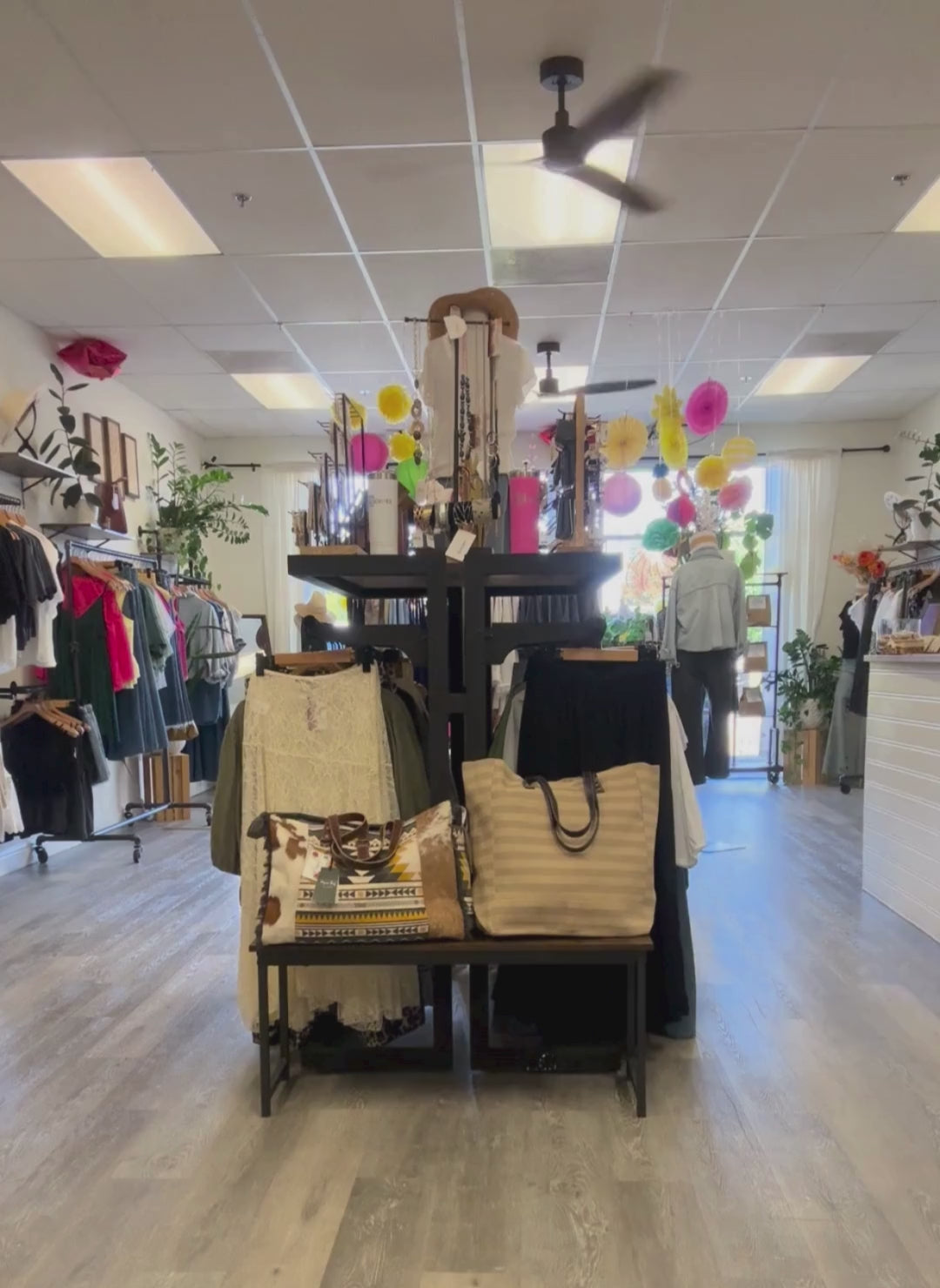 A woman walking with the denim shirt on, black denim jeans inside of August Boutique.